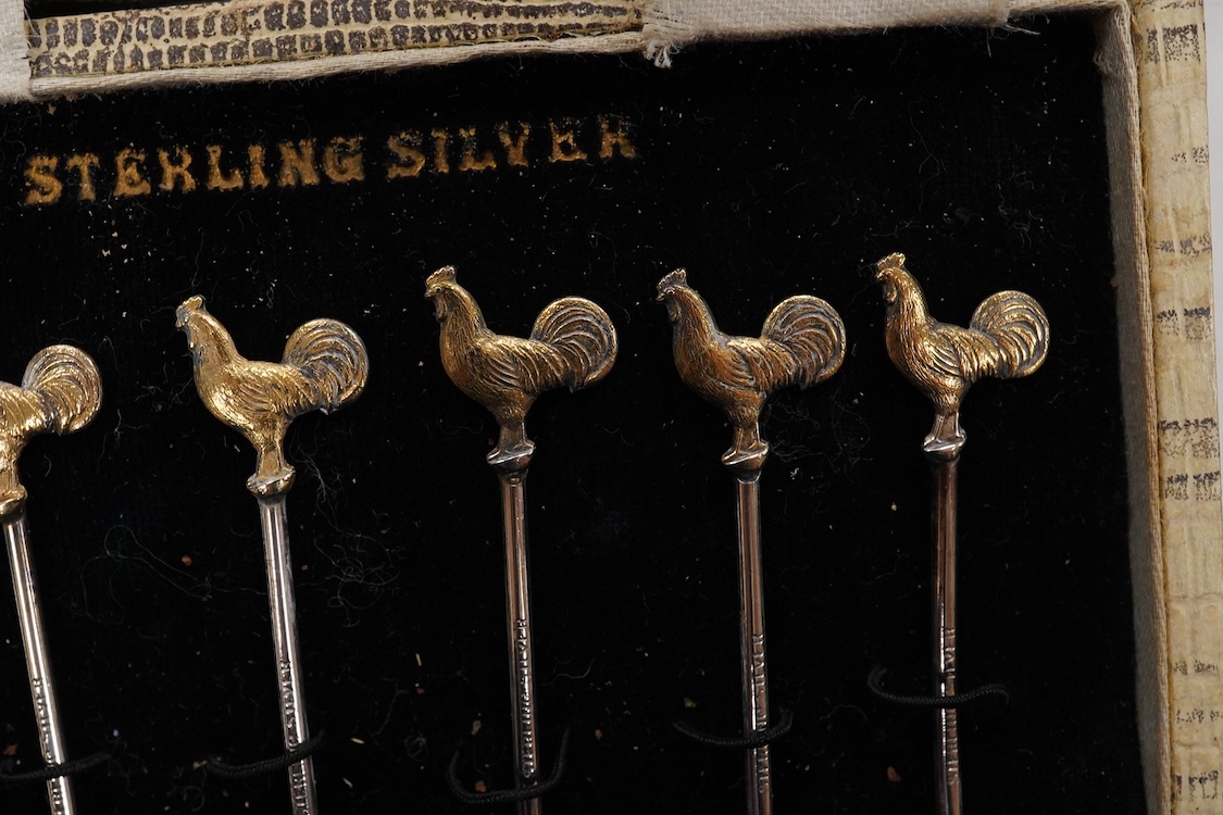 A collection of assorted silver to include five napkin rings including two pairs, a cased pair of glass butter dishes with silver butter knives, five golf related teaspoons, a cased set of six sterling cocktail sticks wi